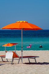 Service on beach, colorful sun bed and parasol for rent on beautiful white sandy beach with crystal clear blue sea water