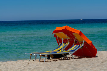 Service on beach, colorful sun bed and parasol for rent on beautiful white sandy beach with crystal...