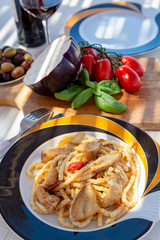 Sicilian pasta dish with traditional busiata pasta and sicilian vegetables, Viola eggplant, tomatoes served ourdoor on terrace