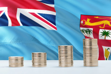 Fiji flag waving in the background with rows of coins for finance and business concept. Saving money.