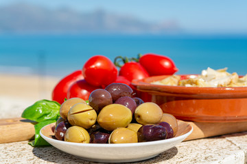 Italian appetizer green and black olives in olive oil, tomatoes and marinated artichokes close up