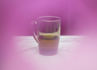 tea in a glass cup on the table, cozy atmosphere on a pink background