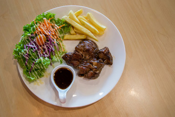 Grilled pork steak and vegetables . plate of grilled pork with french fries and salad on Table. juicy grilled pork chop (neck cut) with greens