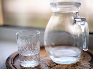 Jug of water and a glass in a tray on the windowsill