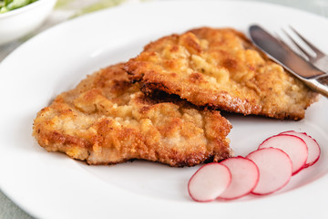 Fried pork chop in breadcrumbs served with radishes.