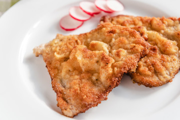 Fried pork chop in breadcrumbs served on white plate