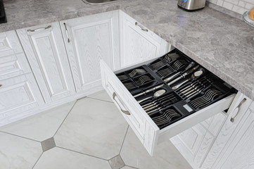 drawer with silver cutlery in modern white kitchen