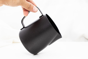 Black milk stainless pitcher object make coffee on white table and fabric background