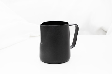 Black milk stainless pitcher object make coffee on white table and fabric background