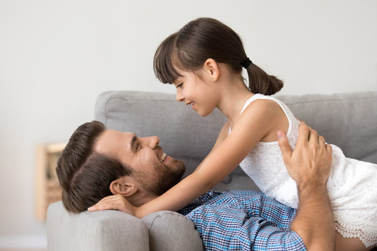 Cute girl relax with young dad lying on sofa