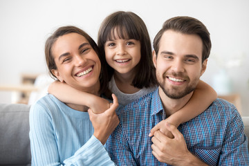 Family picture of funny preschooler hug smiling parents