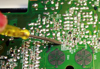 Electrical board with electronic components. High-tech printed circuit board. Screwdriver.