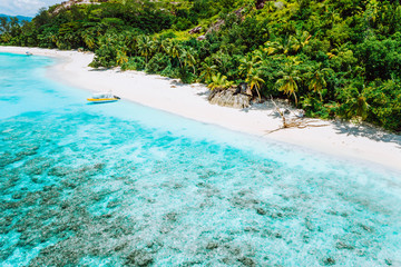 Aerial view of boat moored at uninhabitable island with tropical beautiful azure blue lagoon, Seychelles