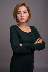 Portrait of beautiful Asian businesswoman against gray background