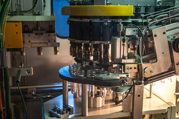 View inside industrial automated machine for blowing plastic bottles from PET preforms, conveyor belt in juice and water plant production