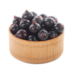 heap of black currants in wooden cup isolated on white background