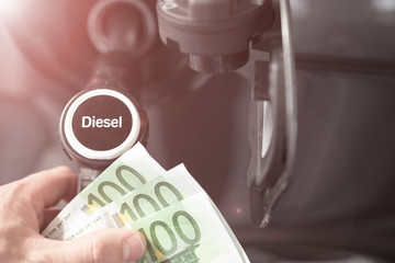 Tanken und Autofahren wird teuerer, Mann mit Geldscheinen an der Zapfsäule an der Tankstelle