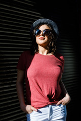 Young pretty brunette walking around the city on a sunny day, dressed in summer clothes, and a hat...