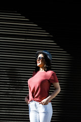 Young pretty brunette walking around the city on a sunny day, dressed in summer clothes, and a hat on her head. Summer style