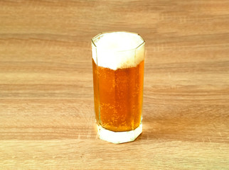 Beer with foam in glass beaker on wooden background. 