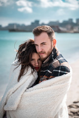 Couple is standing on the beach, posing for the camera