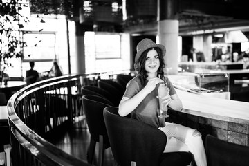 Young pretty cute brunette sitting in a restaurant behind a bar and drinking a cocktail. Summer style