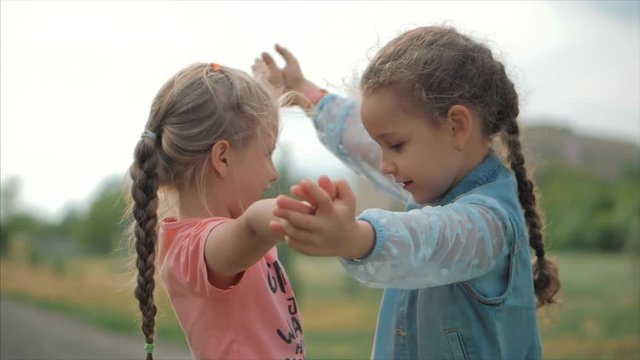 Two smiling, curly, cute sisters baby-girls hug tightly each other. Happy childhood, positive emotions, true feelings.