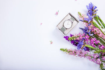 Female hand watch in gift box surrounded with flowers. Present for holiday. Flat lay