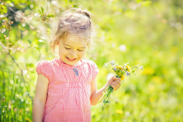 Happy little girl playing with bouquet in sunny park