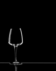 Dark field lighting technique hilights the edges of a wine glass and table on black background. Copy space