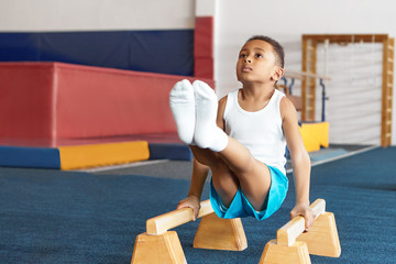 Seld determined disciplined African American little sportsman in white t-shirt, socks and blue...