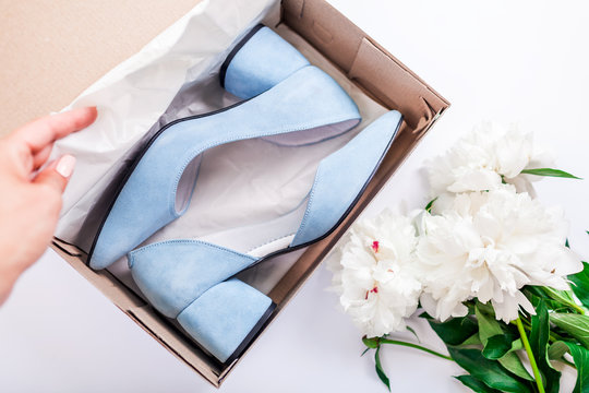 Female blue wedding shoes in box with flowers on white background. Woman opens box