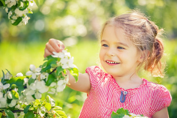 Happy little girl playing in spring apple tree garden