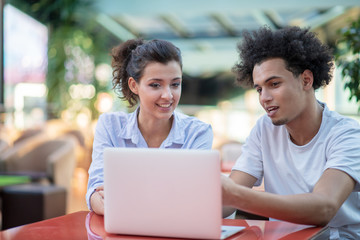 Interracial couple using tablet computer in coffee shop