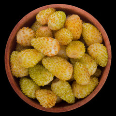 heap of  yellow wild strawberry in wooden cup isolated on black. top view