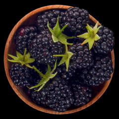 blackberry in wooden cup isolated on black background. top view