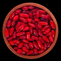 barberry in wooden cup isolated on black background. top view