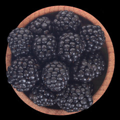 blackberry in wooden cup isolated on black background. top view