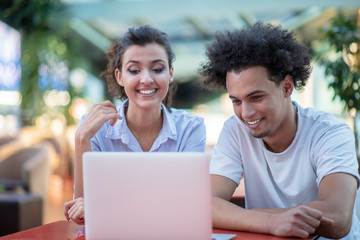 Interracial couple using tablet computer in coffee shop