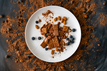 top view of the dessert with chocolate bar, blueberry, almond nuts on the white plates