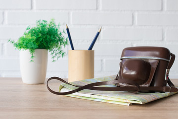 desk with vintage photo camera, map and pen, travel planning