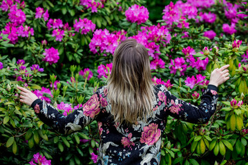 Naklejka premium style woman near rhododendron flowers in a grarden in spring time