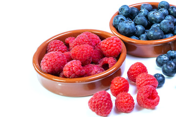 Himbeeren und Heidelbeeren in braunen Schalen