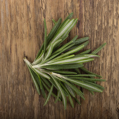 heap of rosemary leaves on wooden background