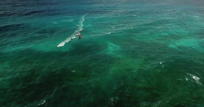 Slow aerial tilt down, Kite surfer in dark blue waters in the Carribean.