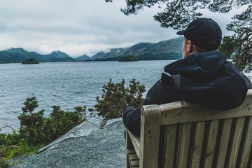 man sitting on bench and looking at the sea