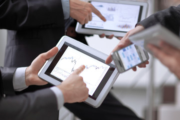 Businessmen at meeting presenting charts on smartphone, tablet