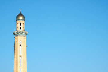 Obraz premium The Golden minaret of the mosque. Muslim symbol on blue sky background. Crescent. Sunset. The concept of religion.