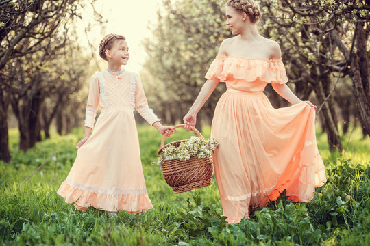 Beautiful cute girls in the garden, enjoying the arrival of spring, dresses in vintage style