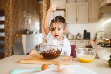 Young kid mixing melted chocolate in a bowl